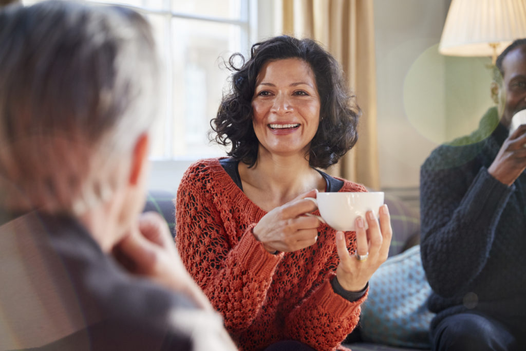 Middle Aged Woman Meeting Friends Around Table In Coffee Shop