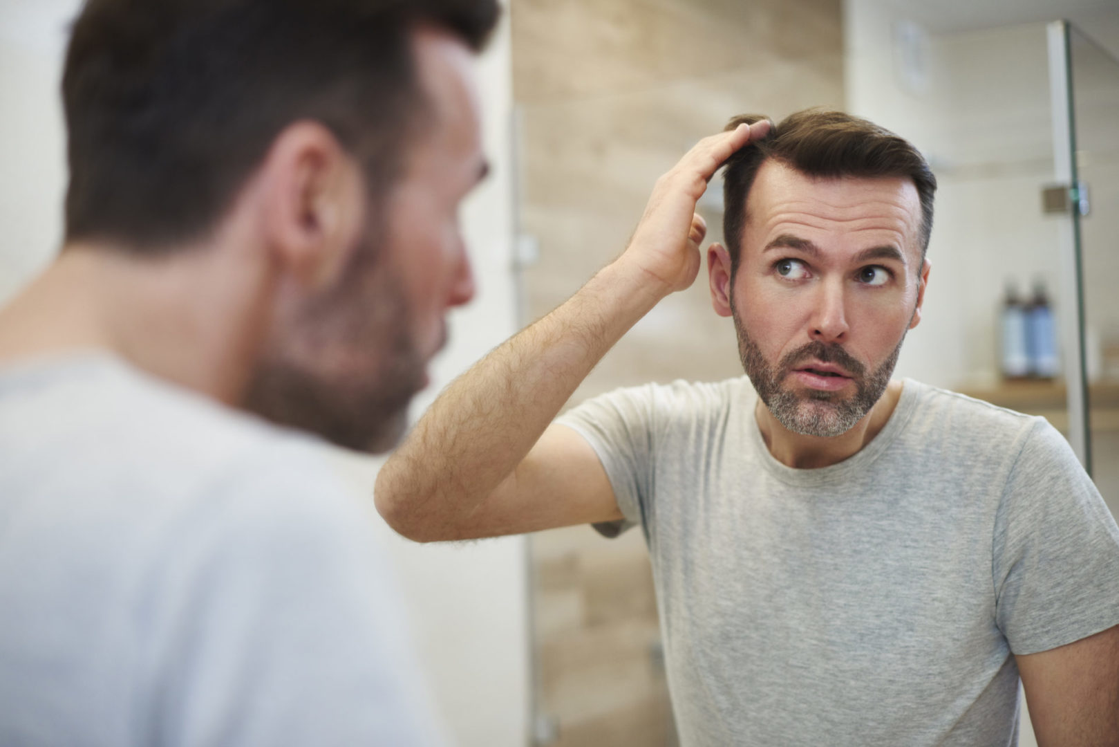 Can a receding hairline grow back? A man checks his hairline in the mirror